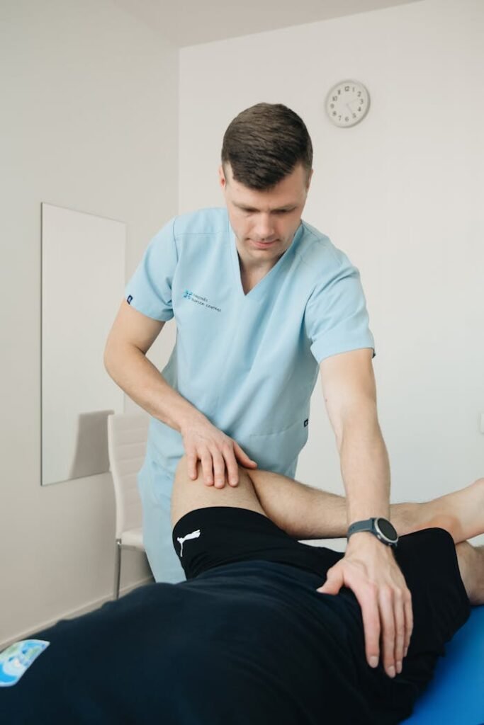 A therapist performs physiotherapy on a patient's leg in a clinical setting, focusing on rehabilitation.