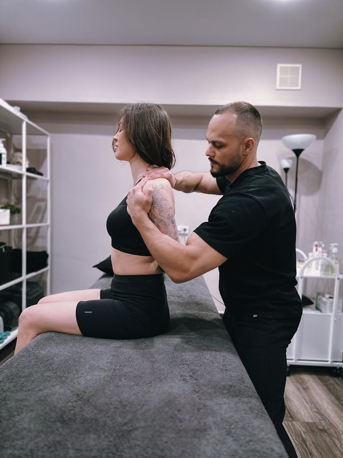 Chiropractor adjusting female patient's shoulder in a contemporary clinic setting.