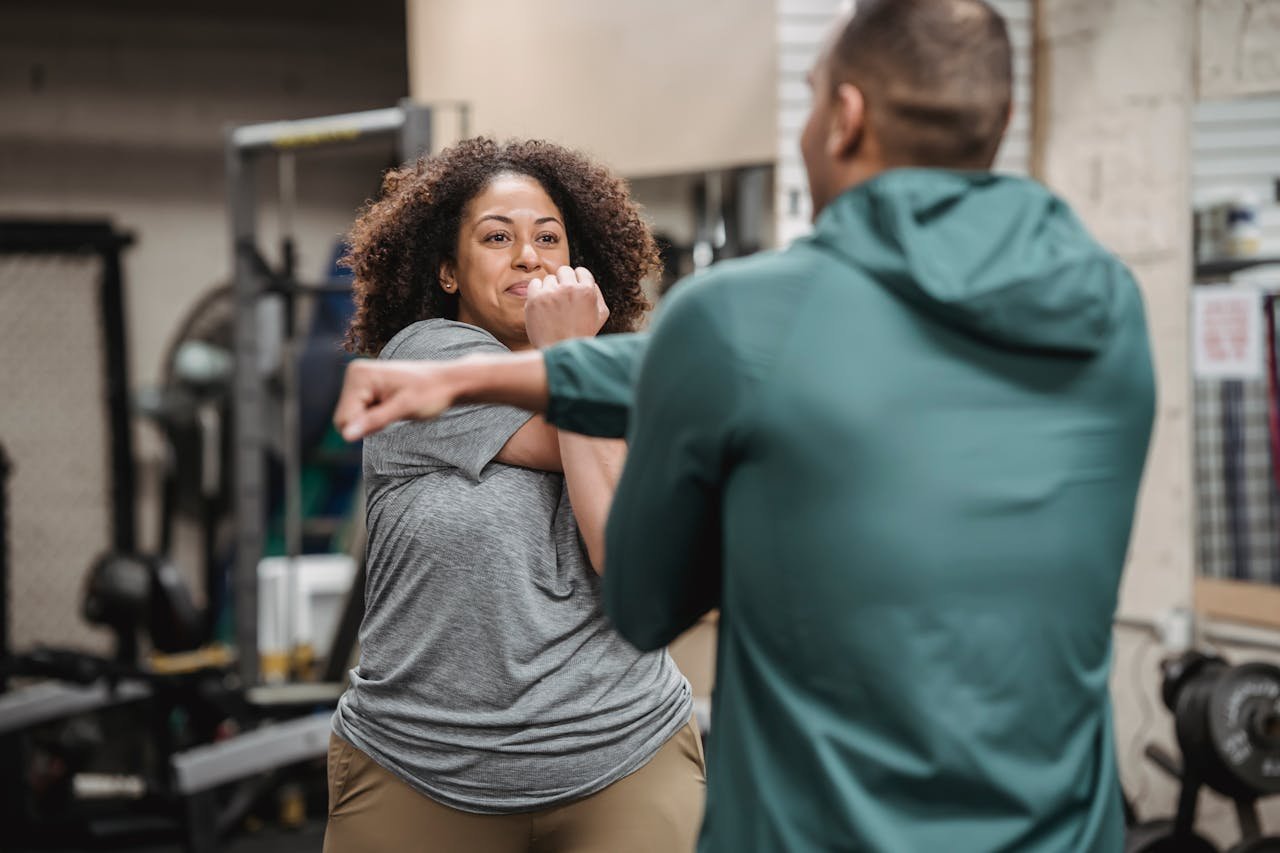 Woman enjoying a stretching session with a trainer in the gym.